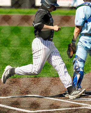 Baseball player in black pinstripe uniform scores a run at home plate as catcher in blue uniform looks on.