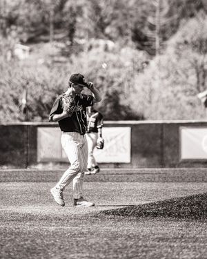 Black and white photo of baseball pitcher winding up on the mound during a game.