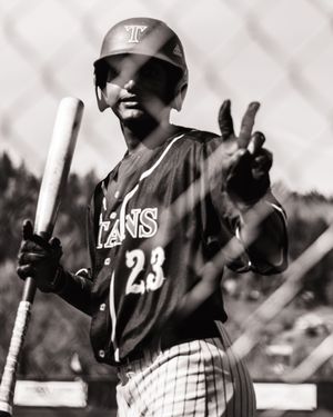 Baseball player number 23 in Titans jersey holds a bat and flashes a peace sign in this black and white photo.