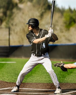 Baseball player #4 in black pinstripe uniform stands ready at bat on a sunny day.