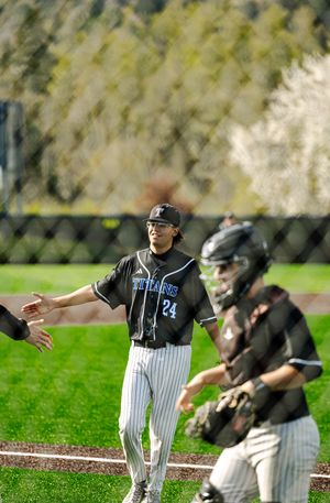 Baseball player number 24 in Titans uniform receives high-five from teammate near home plate during game.