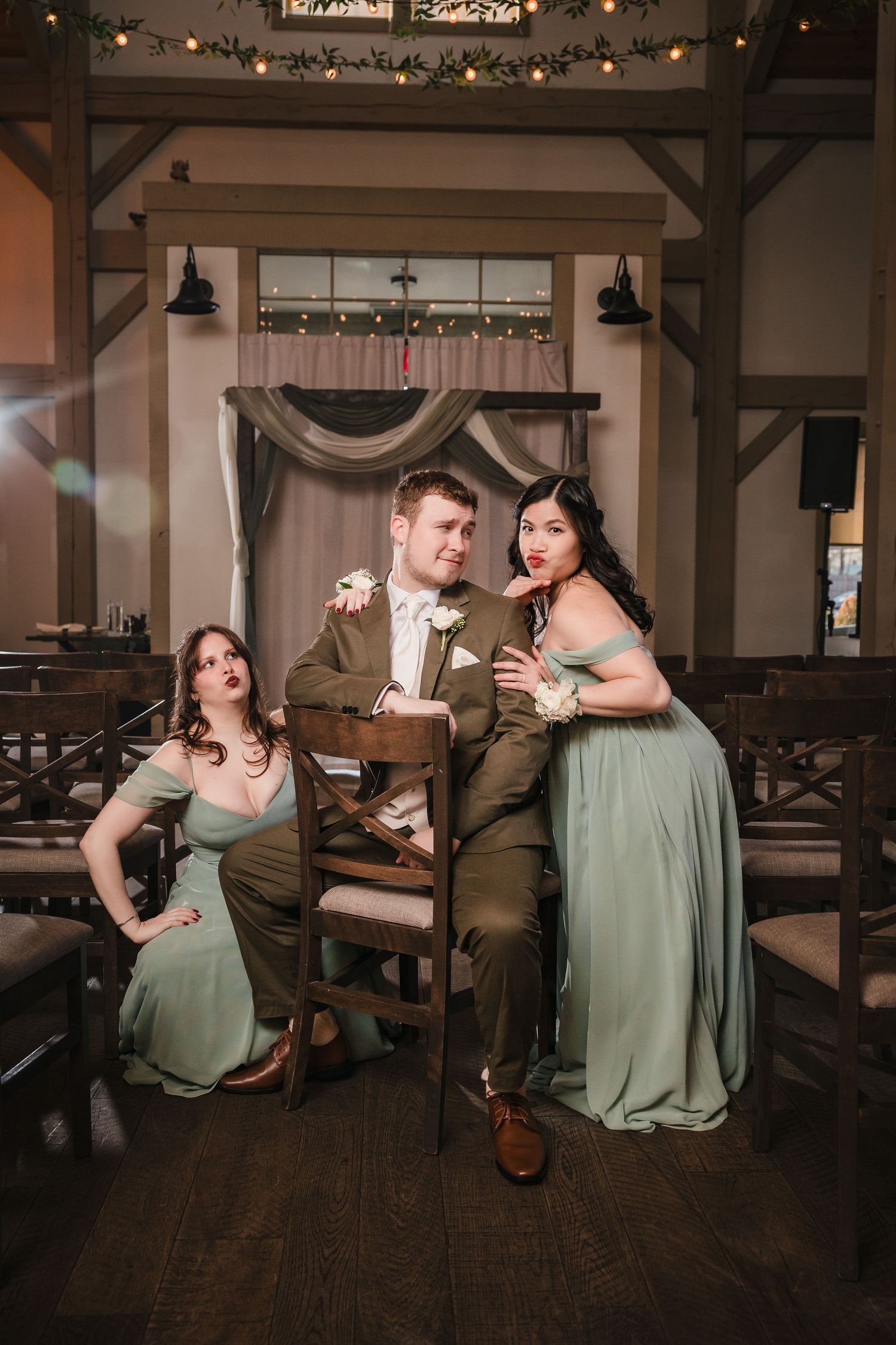 Playful wedding party portrait at Briar Barn Inn ceremony space with groom seated and bridesmaids making funny expressions