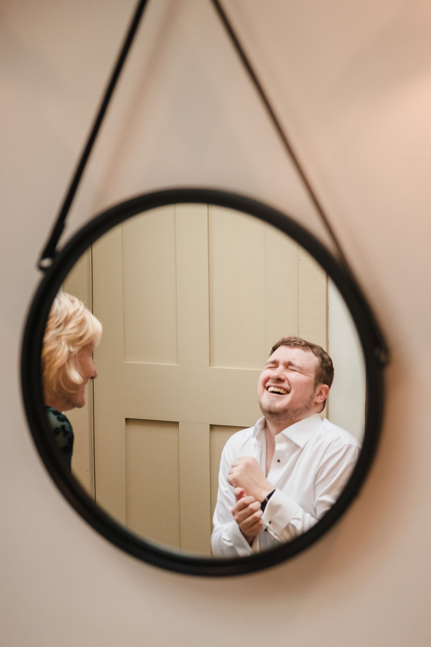 Groom laughing during emotional first look with grandmother reflected in mirror at Briar Barn Inn wedding