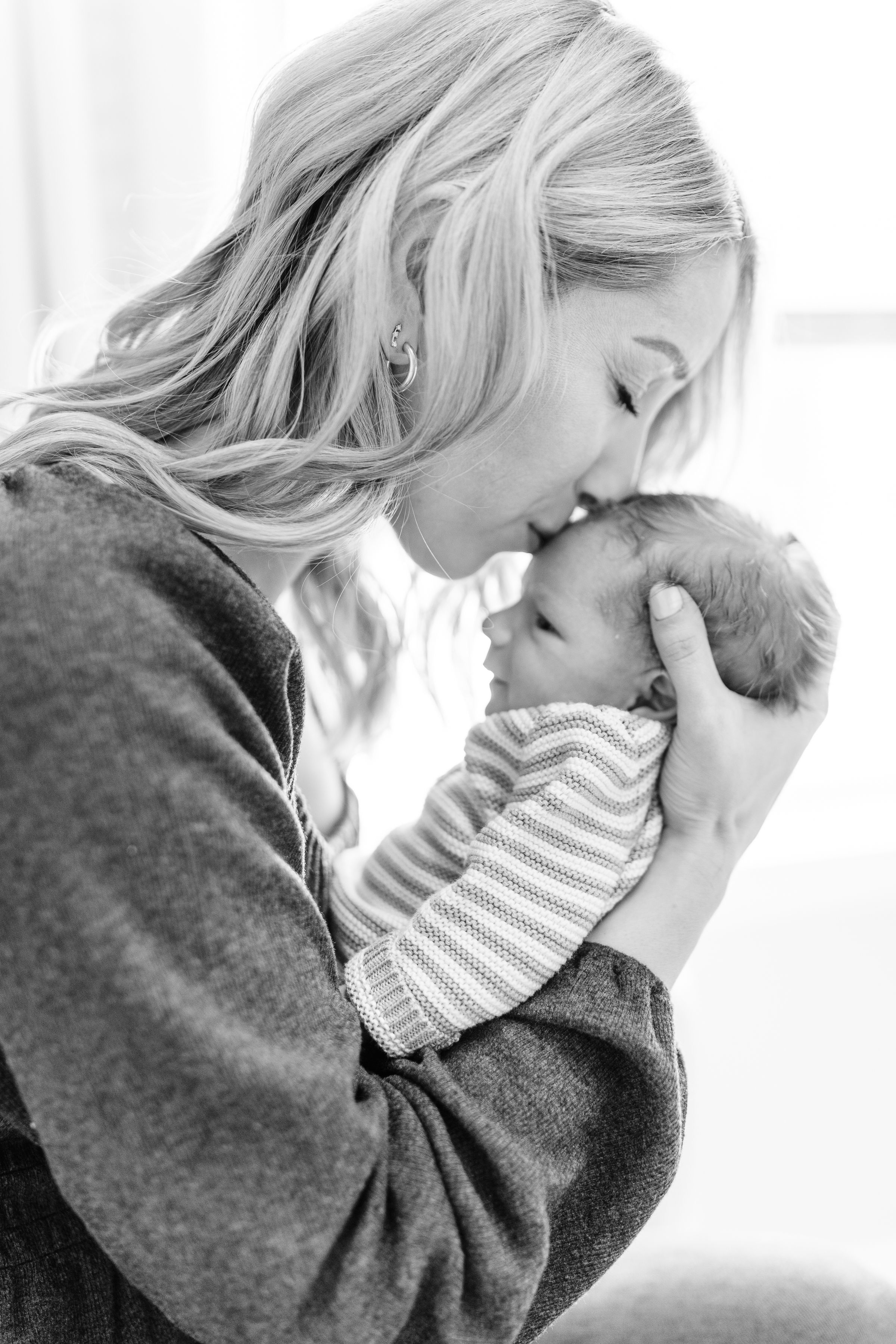 Tender black and white photo of a blonde mother lovingly nuzzling her newborn baby.