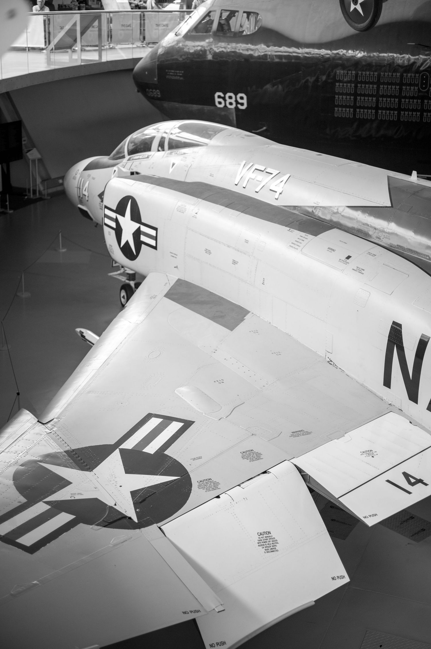 Black and white photo of a U.S. Navy military jet aircraft on display inside a museum, marked with number 14.