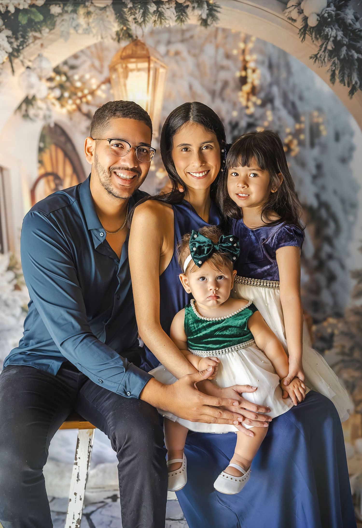 Familia de cuatro integrantes con dos nenas sonriendo tienen trajes de invierno en un fondo de invierno con nieve