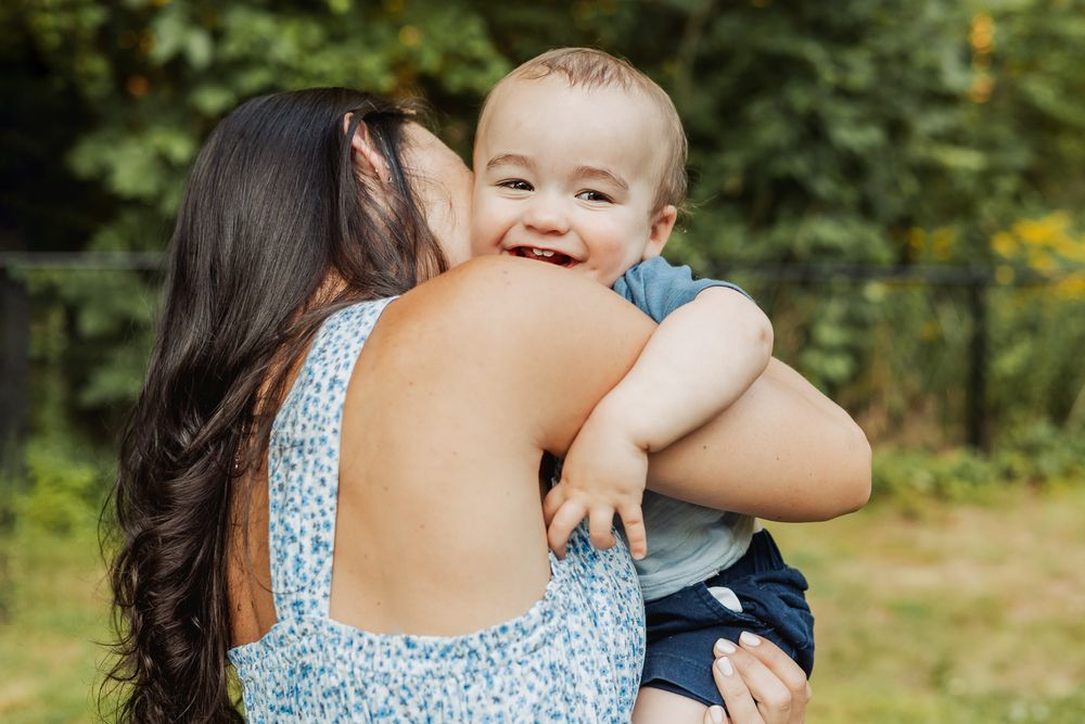 A sweet embrace captured in an outdoor garden setting with natural greenery in the background.