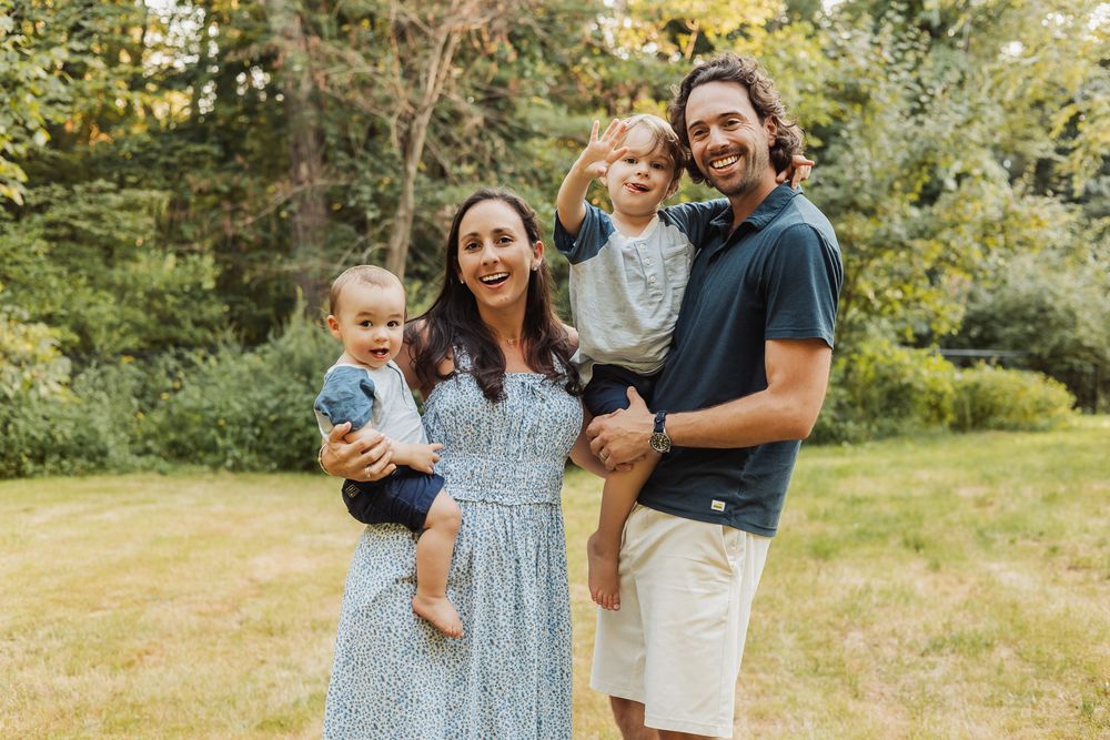 Family enjoying a warm summer day together in a sunny meadow with natural greenery in the background.
