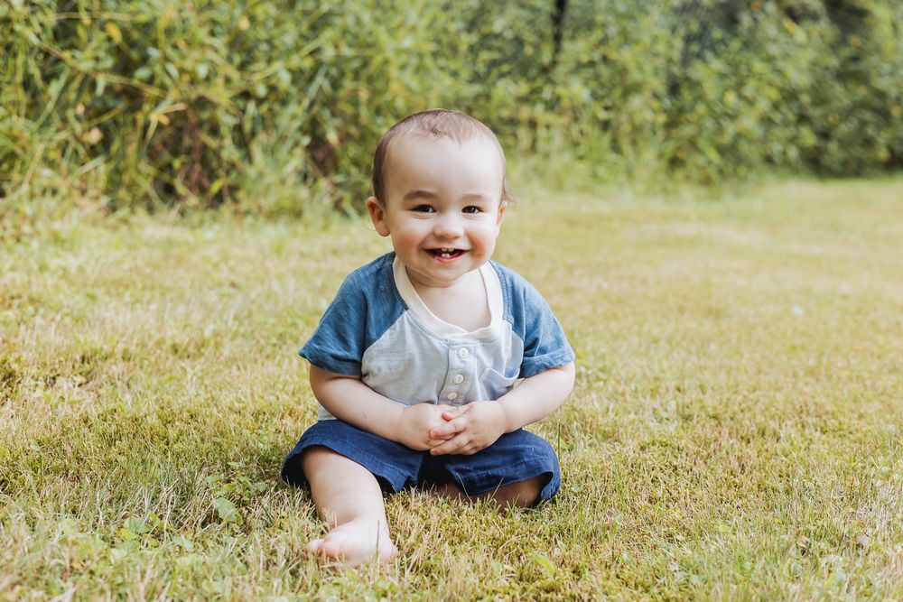 A series of outdoor photos showing a child playing and sitting in a grassy field on a sunny day.