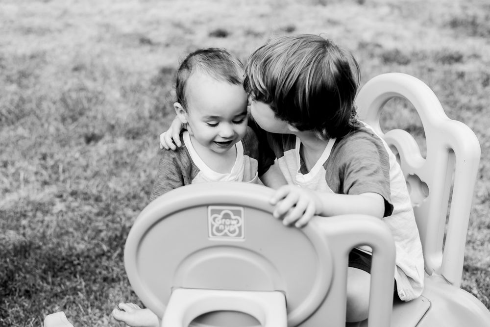 A series of seven black and white photos showing tender moments between parent and child in a backyard setting.