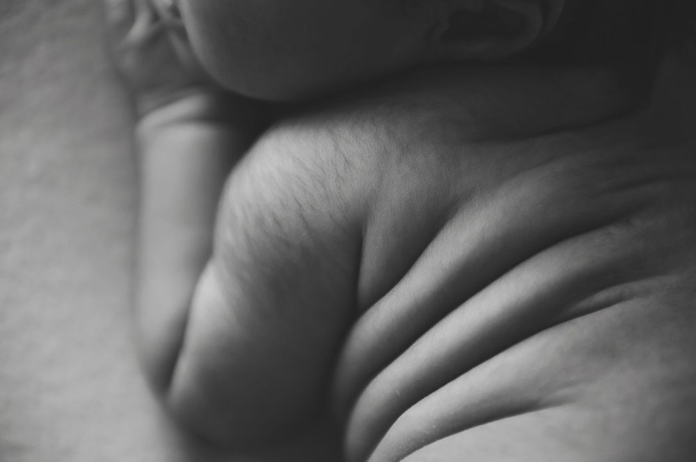 Close-up black and white photograph of baby chunky fat rolls.