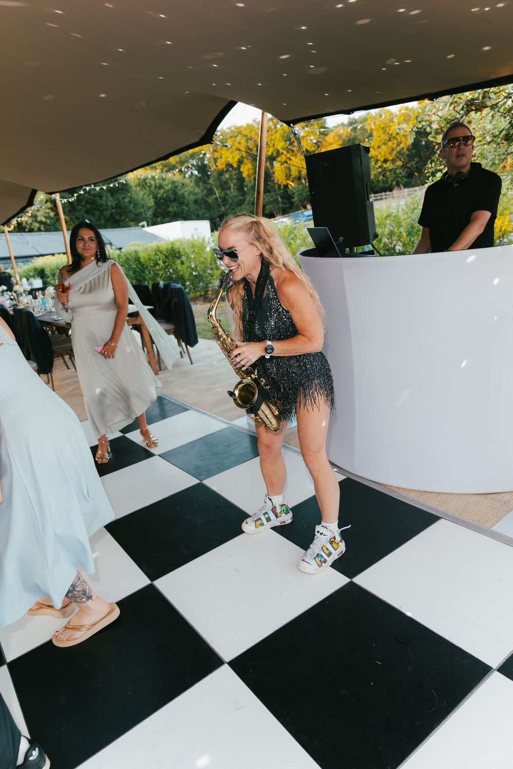 People dancing on a black and white checkered dance floor at an outdoor reception.