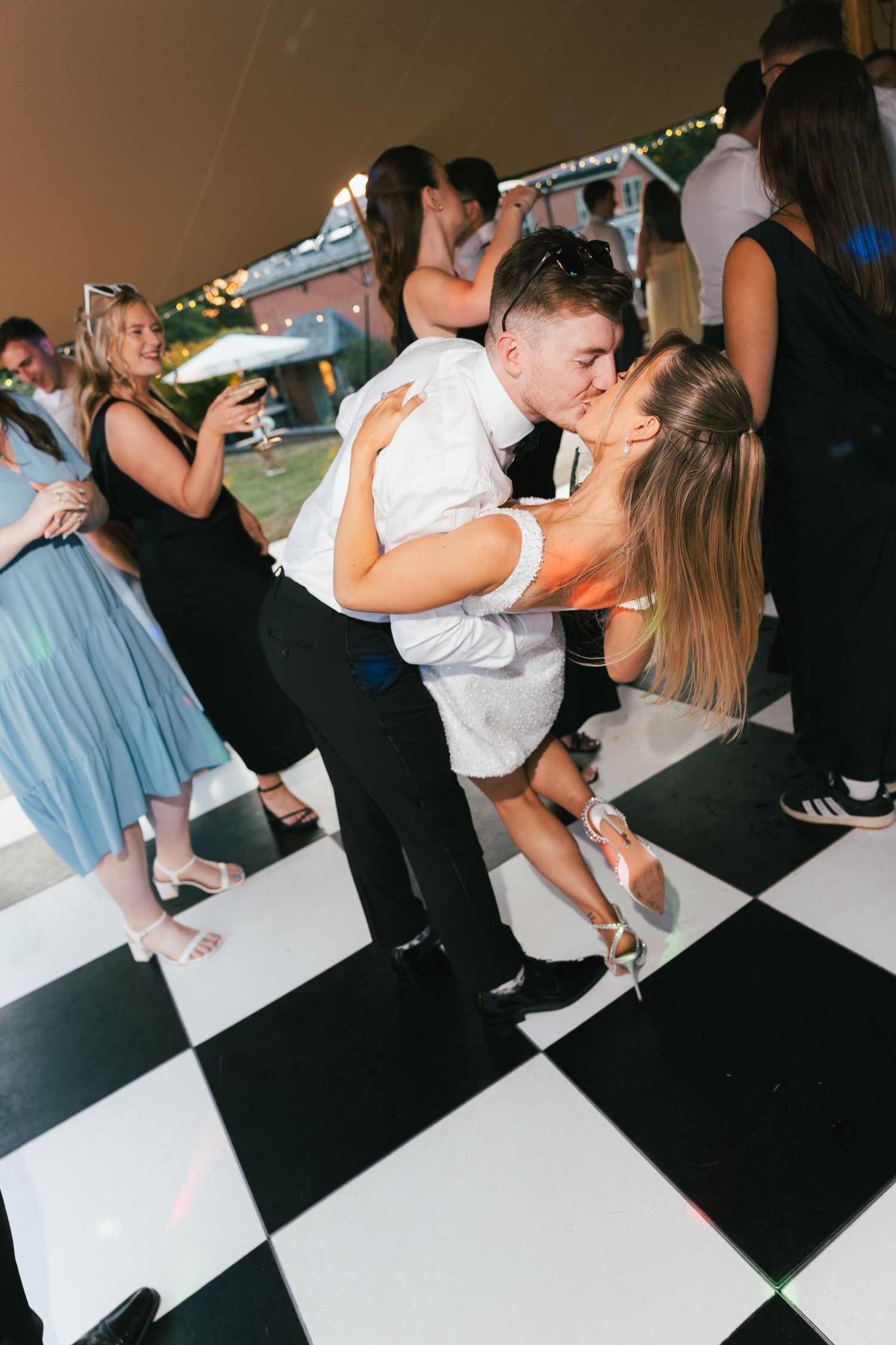 Dancing couples captured in sequence on a checkered dance floor at dusk.