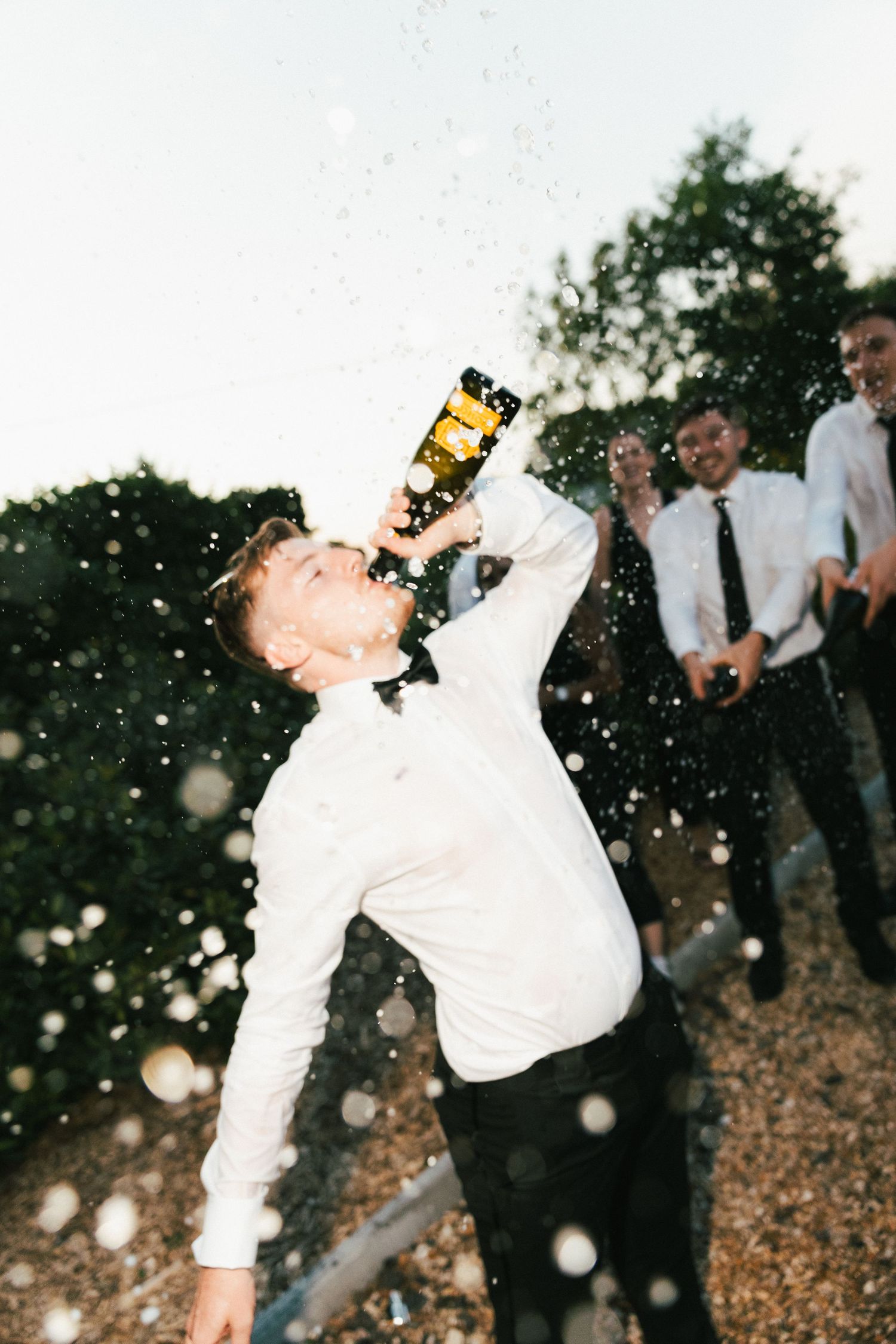 A series showing someone spraying and drinking champagne at an outdoor celebration.