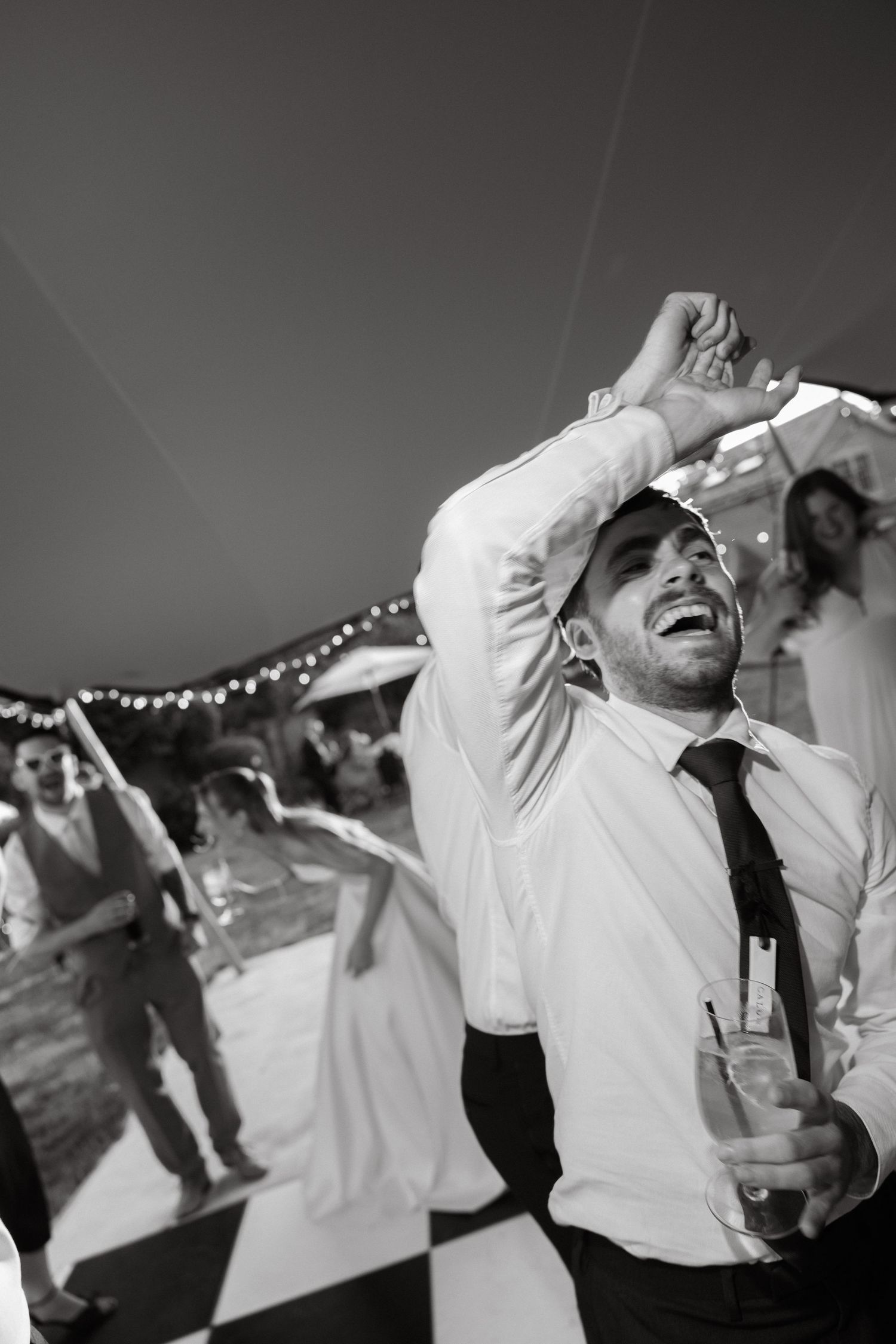 Black and white sequence of party guests dancing under string lights at night.