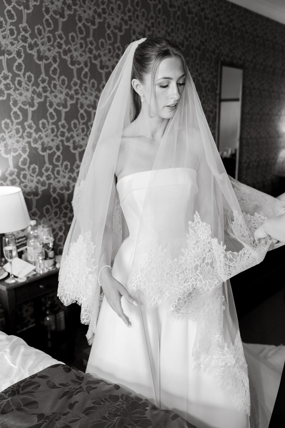 Elegant bridal portrait showing detailed lace veil and strapless wedding gown.