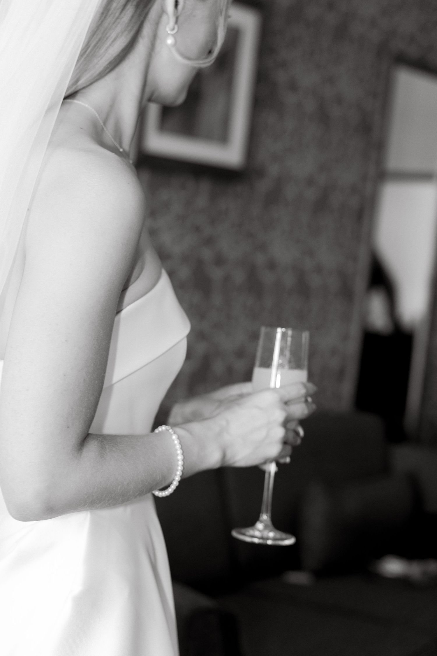 Black and white photo of someone in a strapless dress holding a champagne glass.