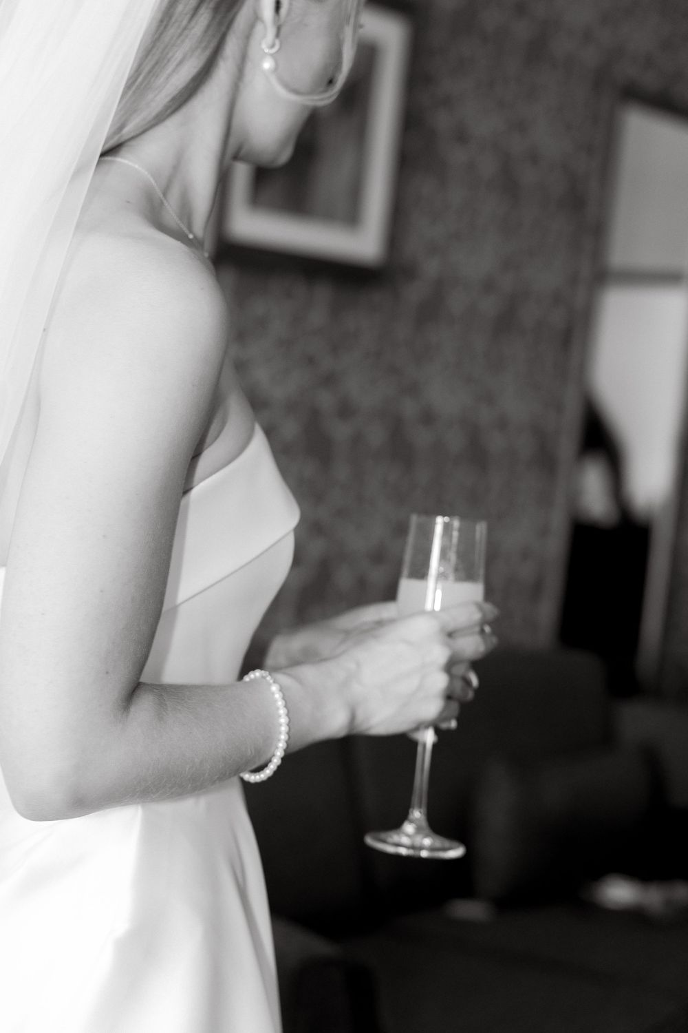 Black and white photo of someone in a strapless dress holding a champagne glass.