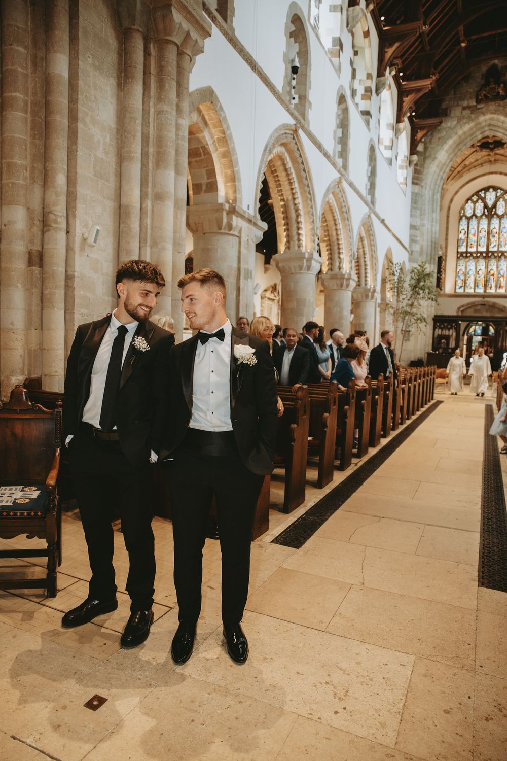 Wedding party members gather in a historic church with vaulted ceilings and stained glass.