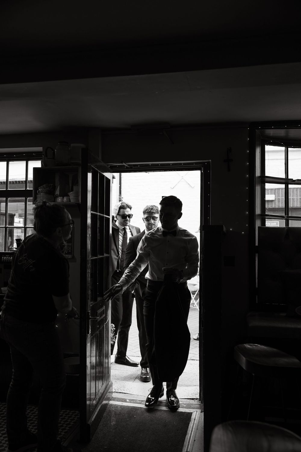 Silhouettes of people walking through a brightly backlit building entrance.
