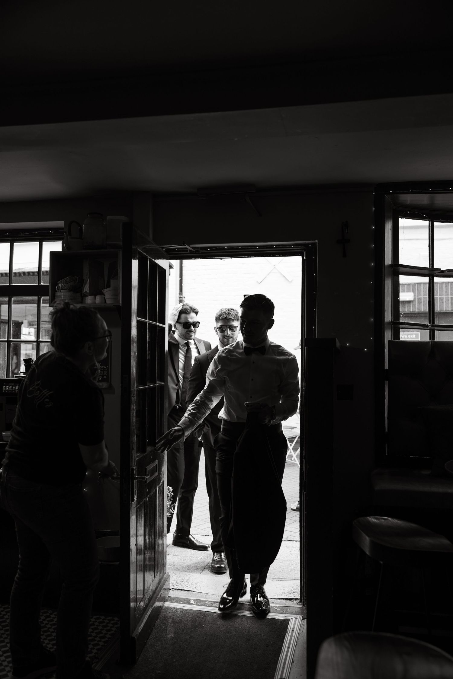 Silhouettes of people walking through a brightly backlit building entrance.