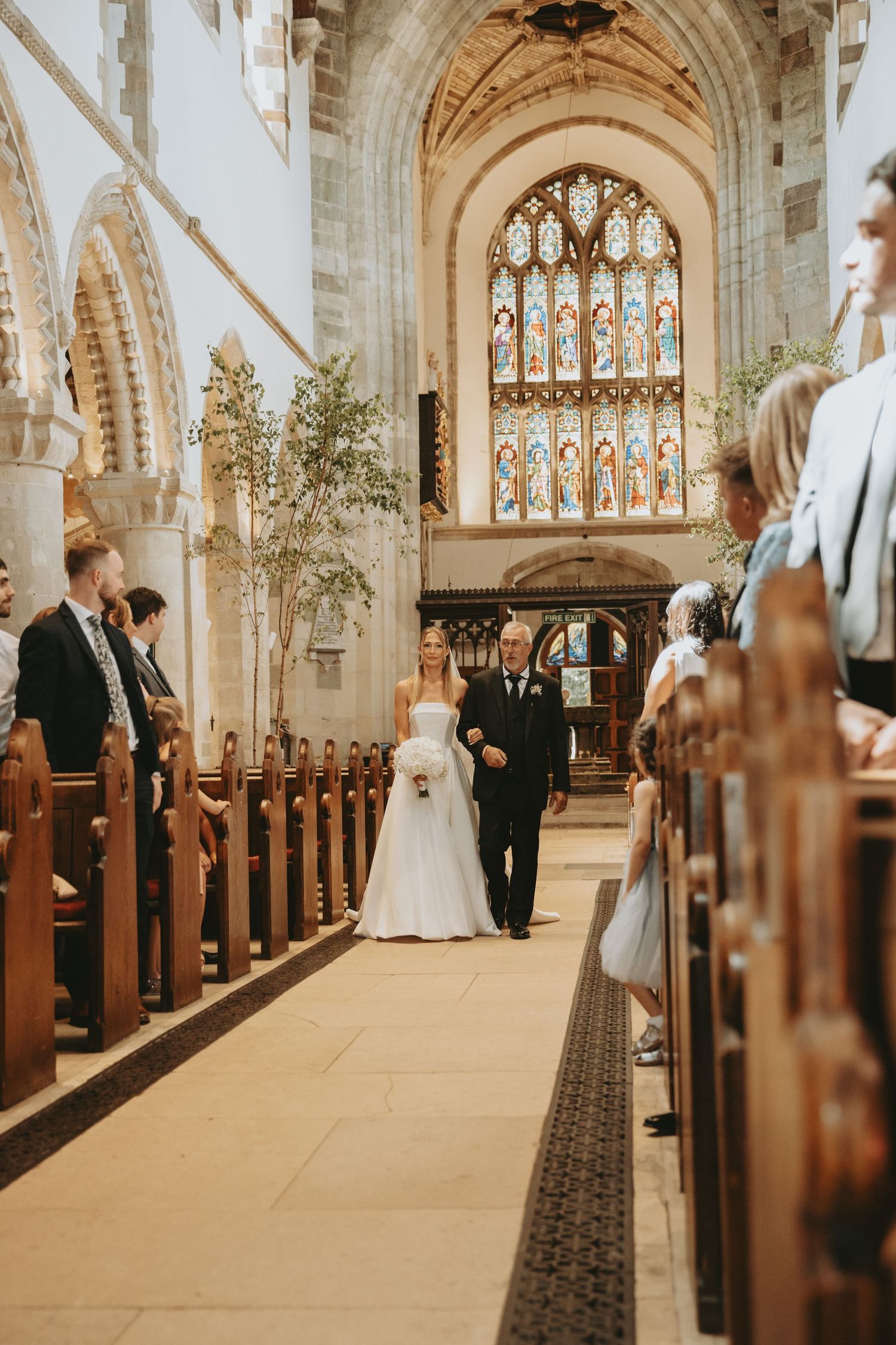 Wedding ceremony processional in a historic church with vaulted ceilings and ornate architecture.