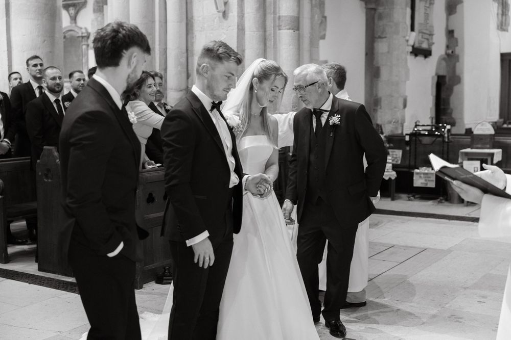 A wedding party celebrates in a grand church hall with stone columns and arched windows.