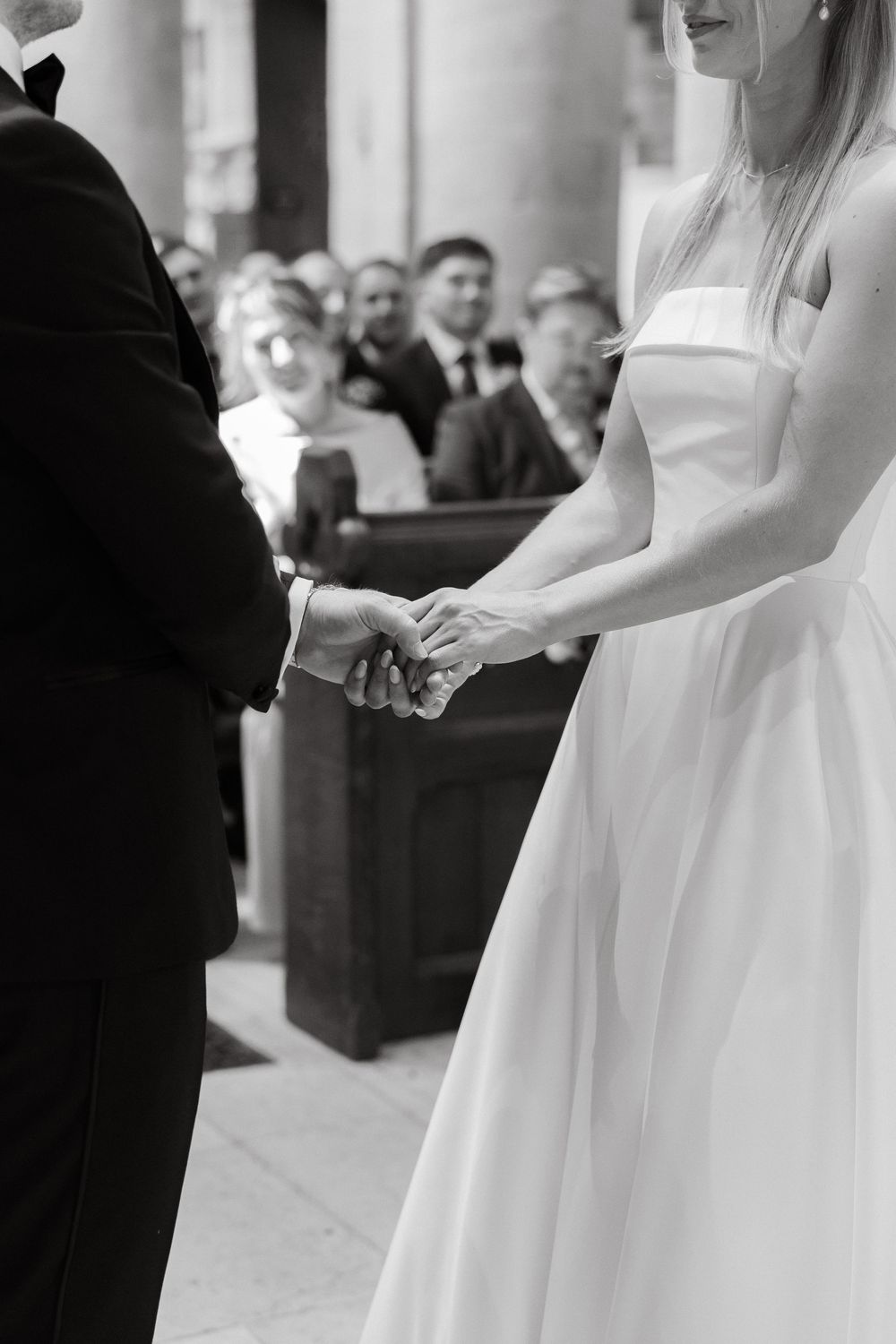Wedding ceremony details showing hands and formal attire in a church setting.