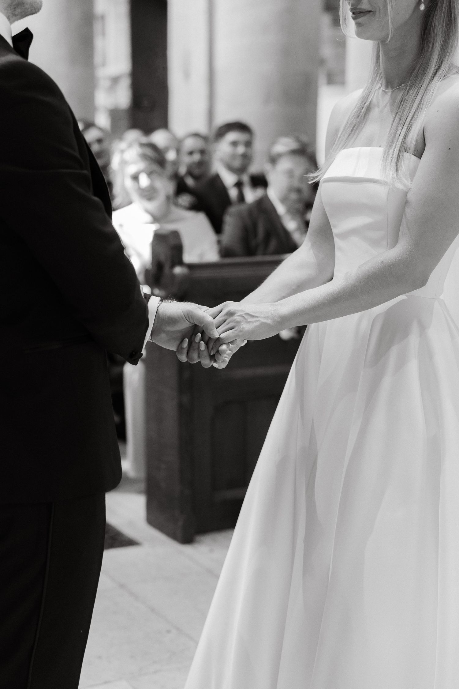 Wedding ceremony details showing hands and formal attire in a church setting.