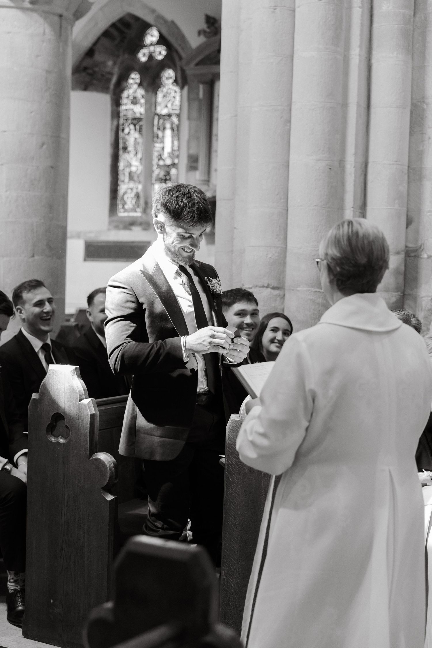Wedding guests mingle in a church colonnade with gothic architecture.