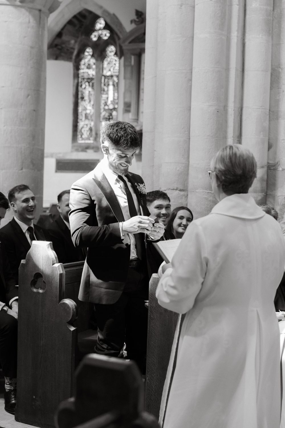 Wedding guests mingle in a church colonnade with gothic architecture.