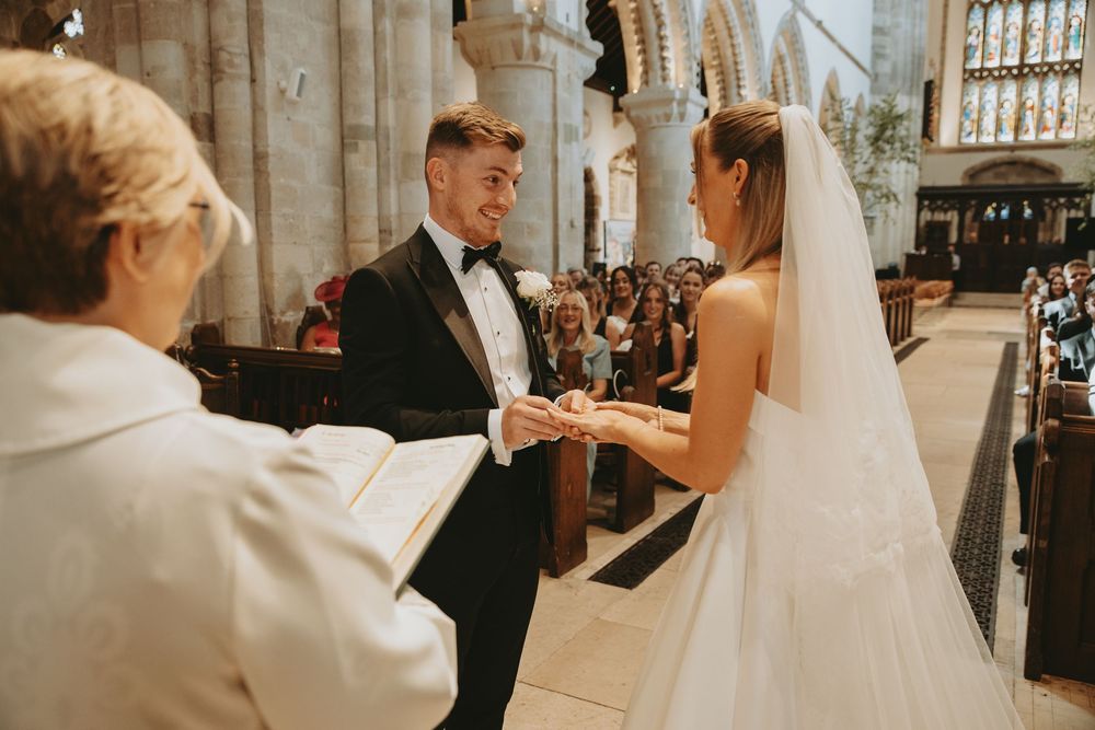 A couple exchanges rings during their wedding ceremony in a historic stone church.