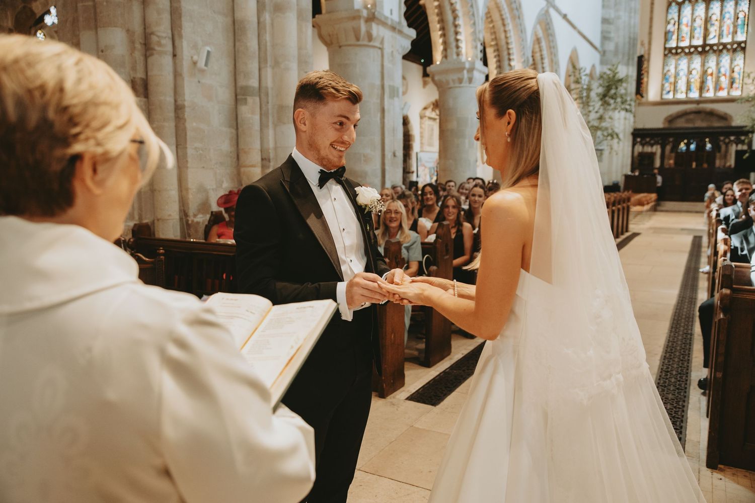 A couple exchanges rings during their wedding ceremony in a historic stone church.