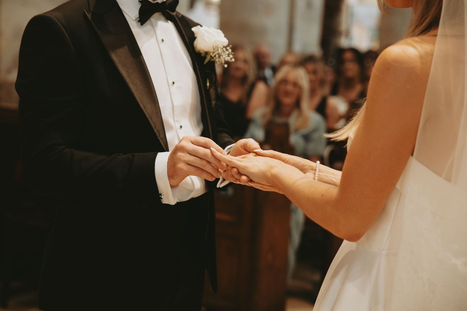 Close-up of hands during a wedding ring exchange ceremony.