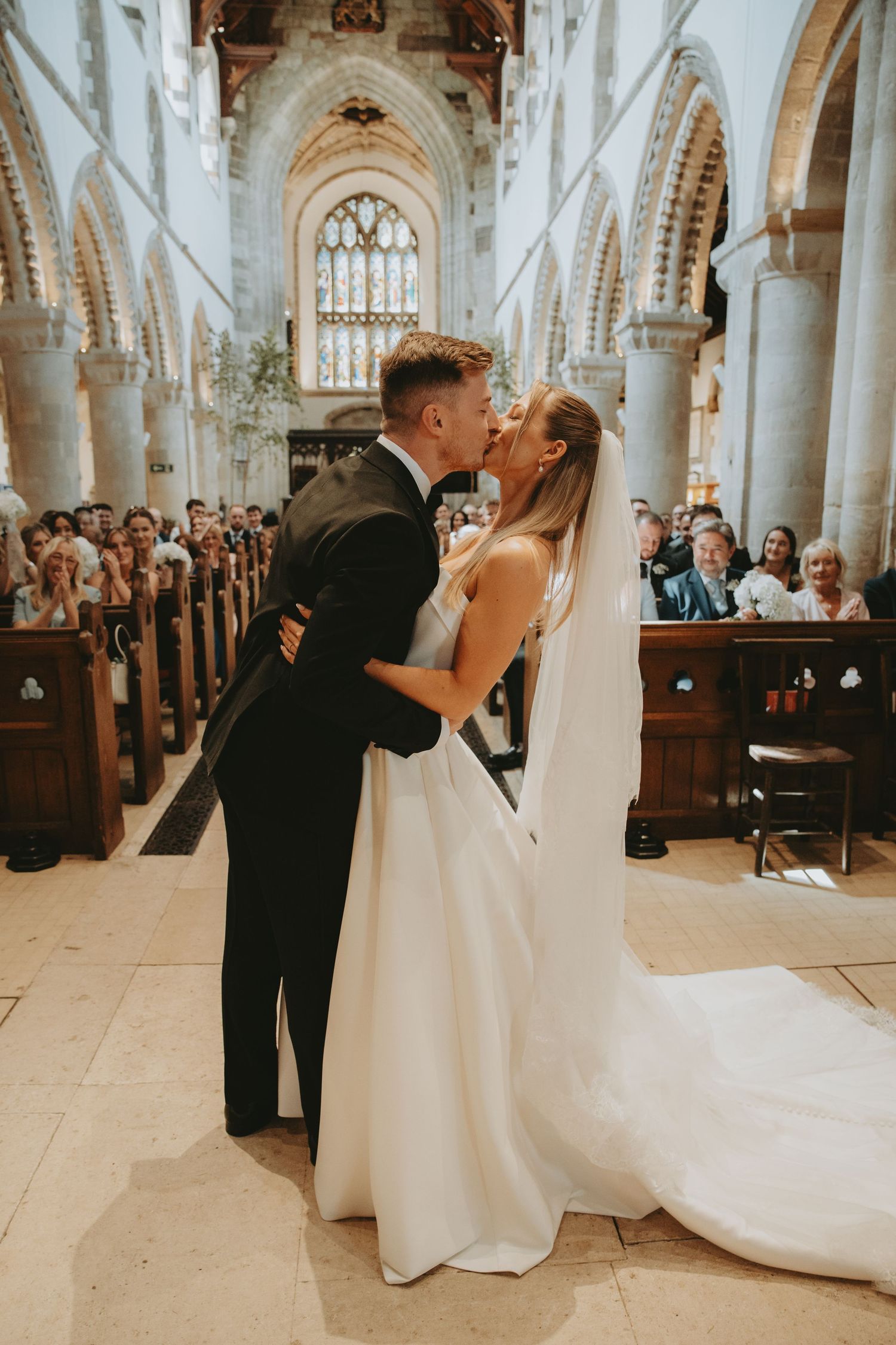 Wedding ceremony taking place in a grand cathedral with white stone columns and arched ceilings.
