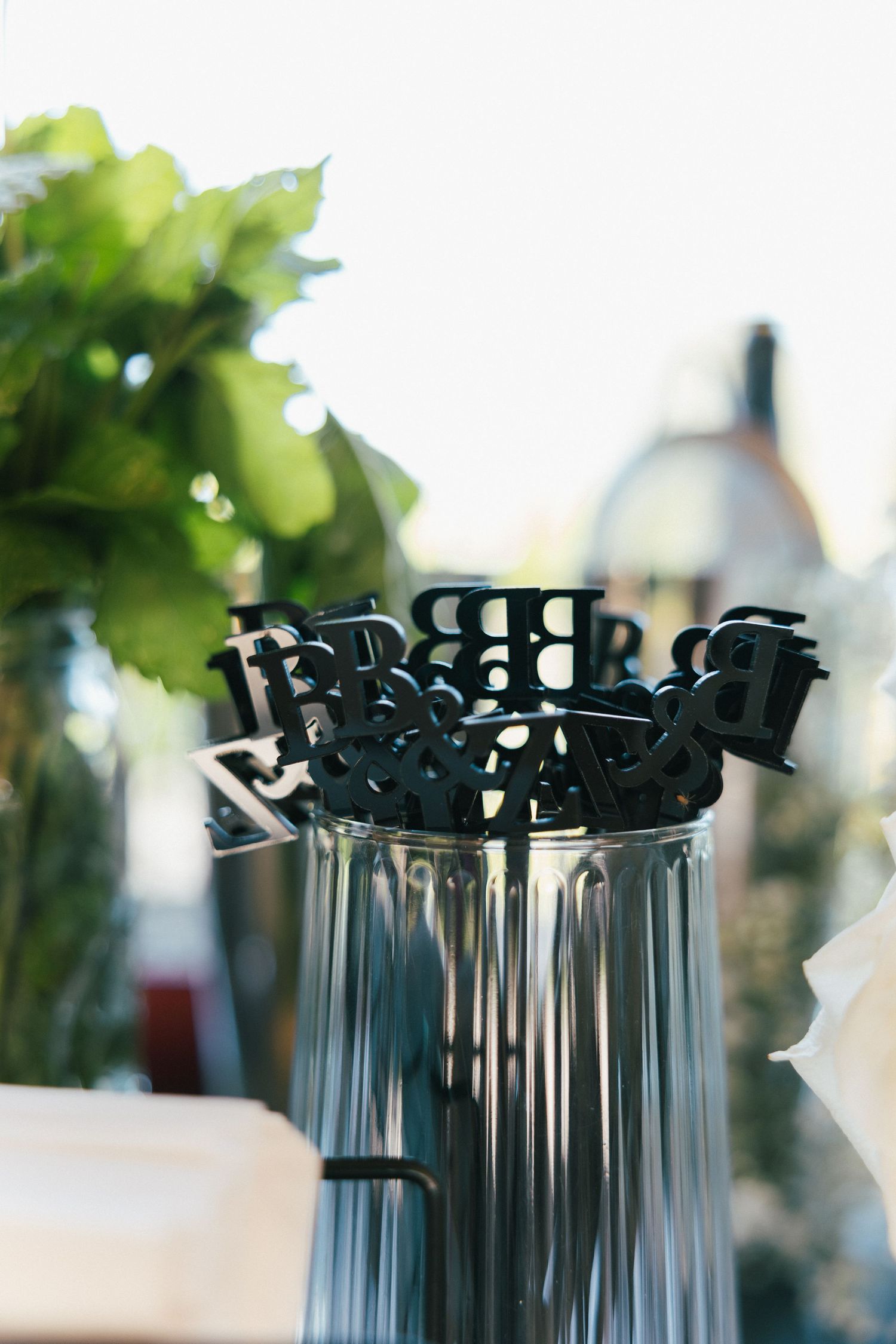 Elegant table settings with decorative black drink stirrers in glass vases.