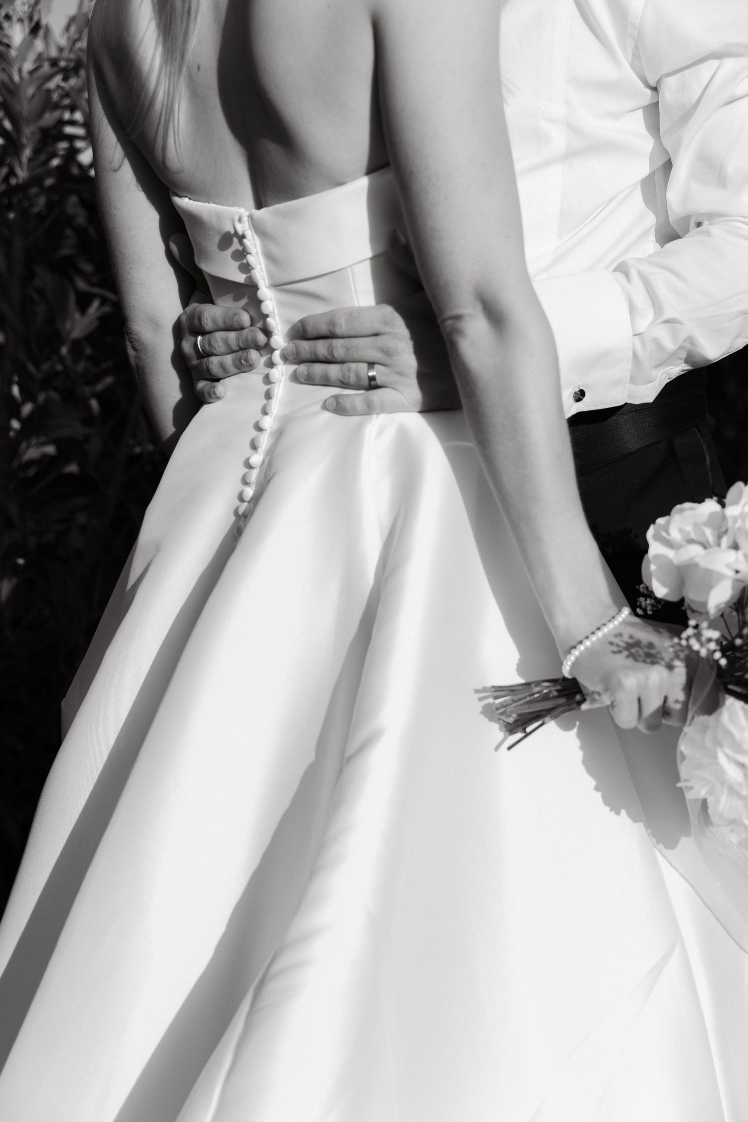 Close-up details of white wedding dress buttons and fabric in black and white.