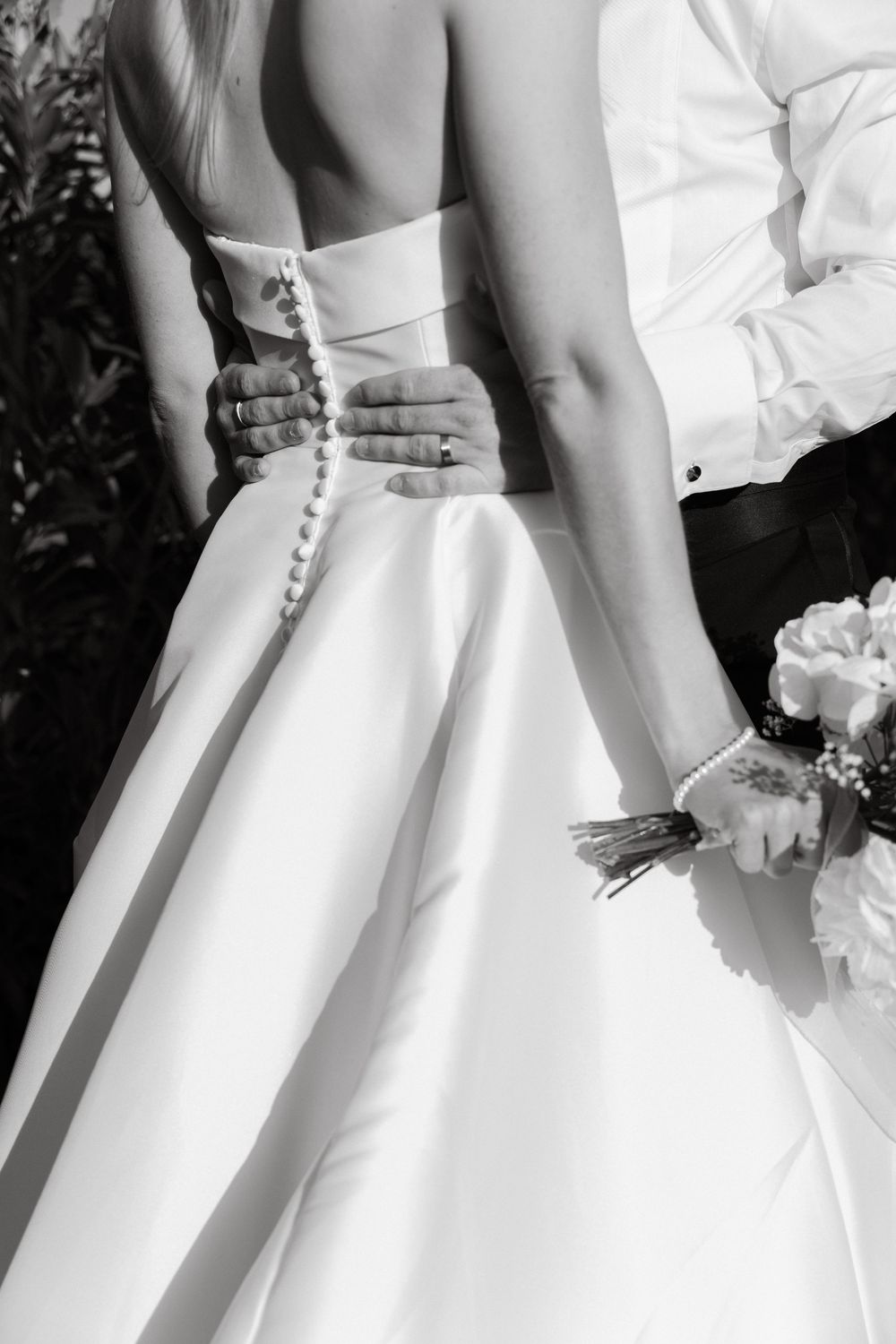 Close-up details of white wedding dress buttons and fabric in black and white.