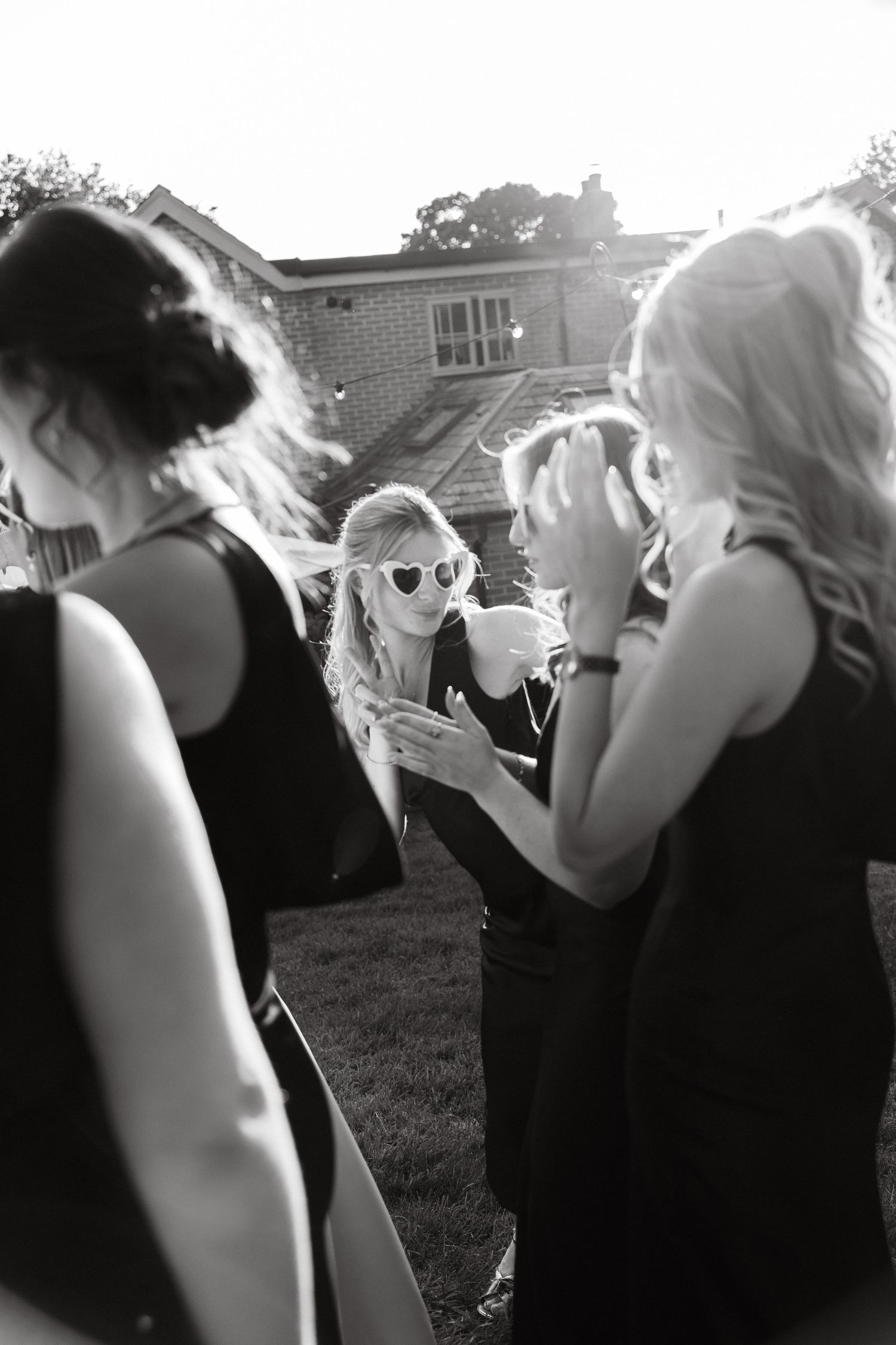 A candid sequence of people in black dresses chatting outdoors.