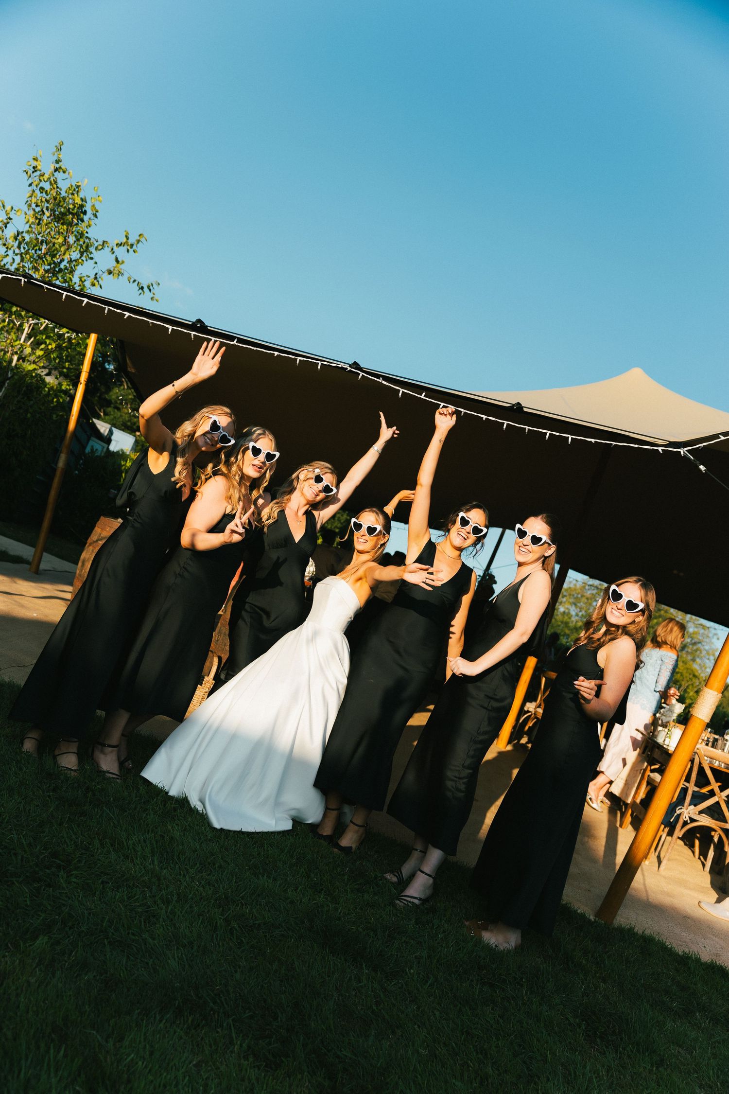 People celebrating under a tent at an outdoor evening party with dramatic lighting.