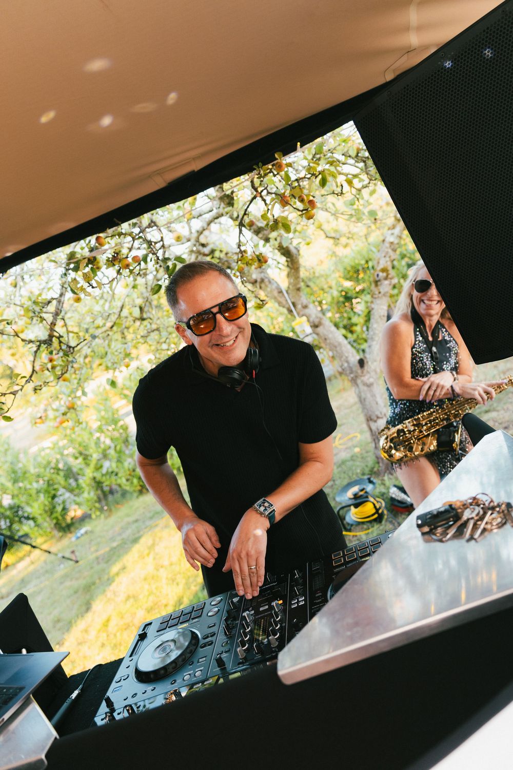 DJ equipment and performers captured in warm sunset lighting at an outdoor event.