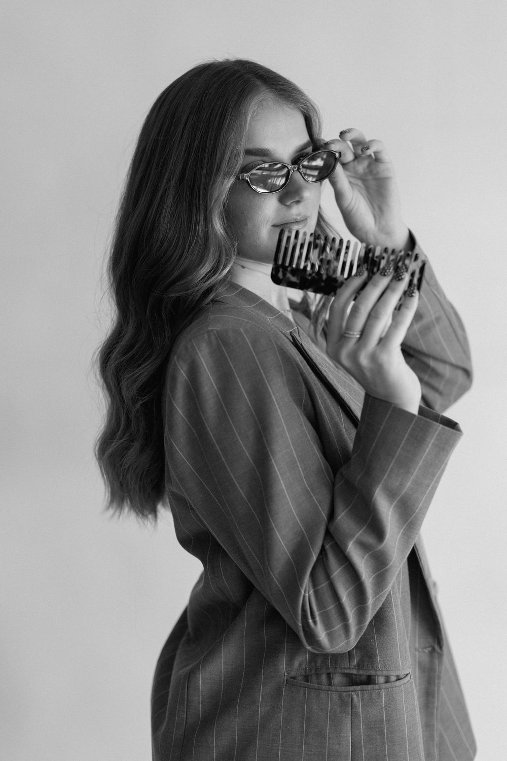 A series of black and white photos showing someone in a pinstriped blazer holding a vintage camera.