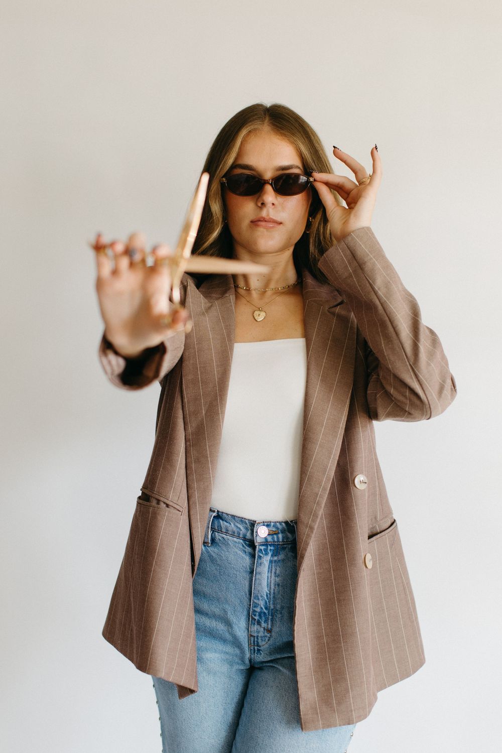 Casual fashion look featuring a brown pinstripe blazer paired with light blue jeans and a white top.