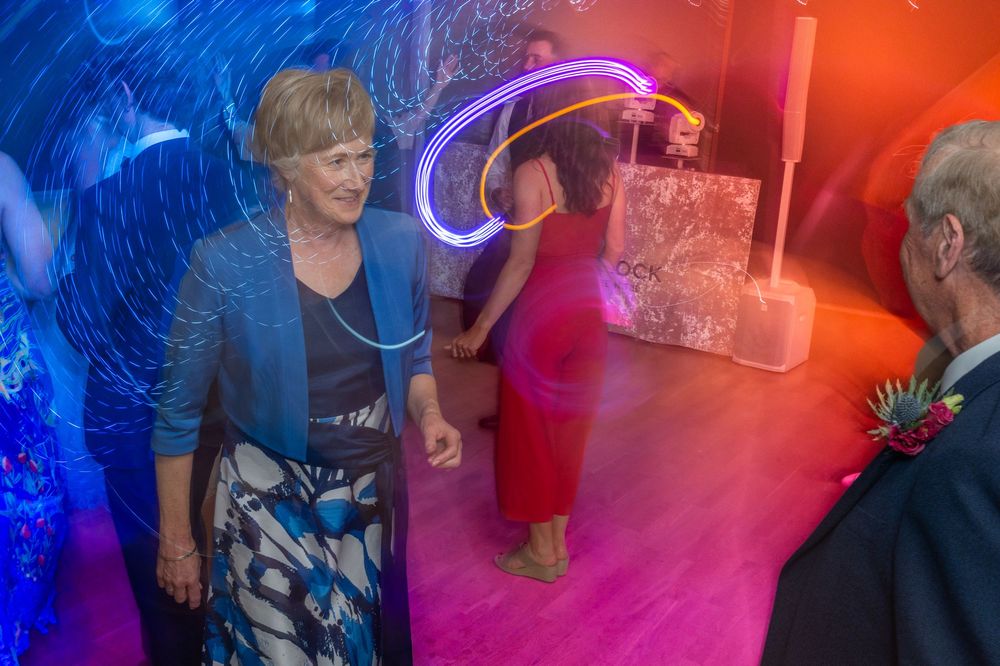 People dancing and socializing in a nightclub with vibrant blue and red lighting effects.