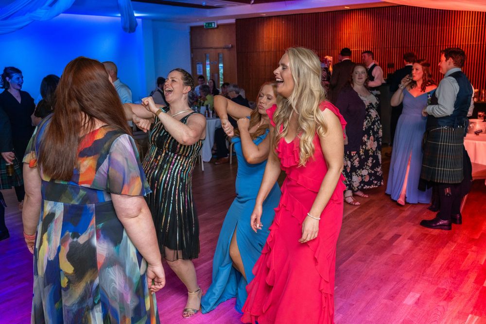 People dancing together on a dance floor illuminated by vibrant blue and red lighting at a social event.