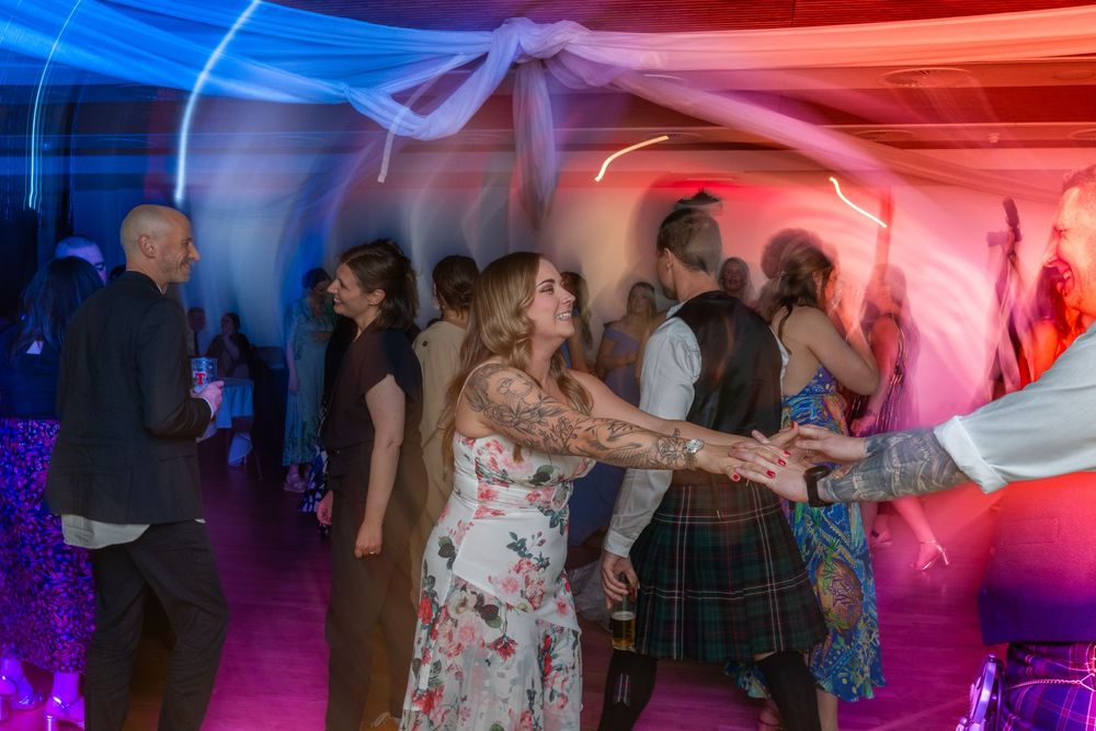 People dancing together in a dimly lit venue with vibrant red and blue lighting effects creating an energetic atmosphere.