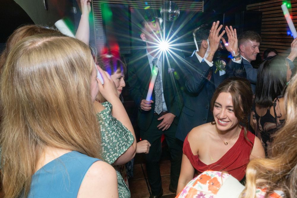 People dancing and socializing at a crowded nightclub with colorful lights and disco effects in the background.