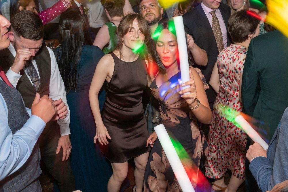 People dancing and socializing at a lively nightclub party with colorful lights and festive atmosphere.