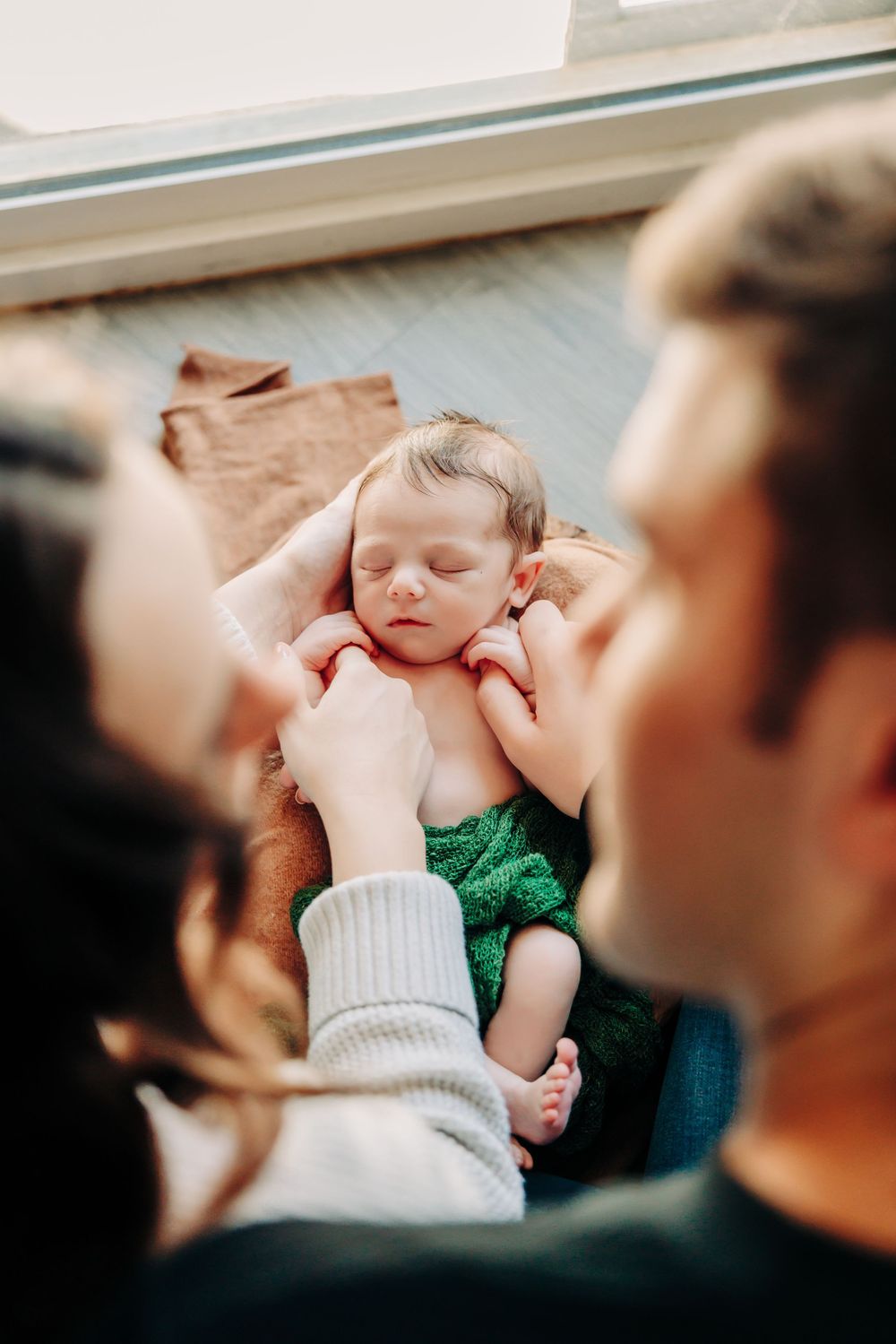 A tender moment shows a sleeping baby being gently touched by caring hands.
