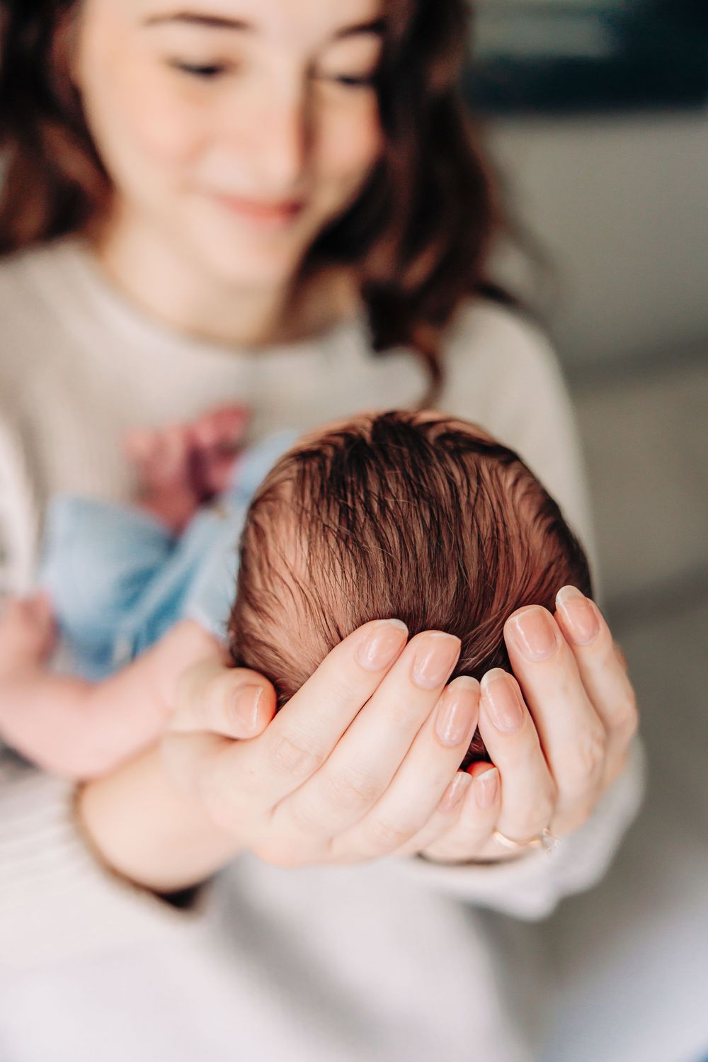 A series of close-up shots showing hands gently cradling a newborn baby in soft lighting.